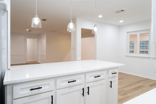 18007 Ravenfield Dr, Houston, TX 77084 - kitchen with light countertops, light wood-type flooring, pendant lighting, visible vents, and white cabinets