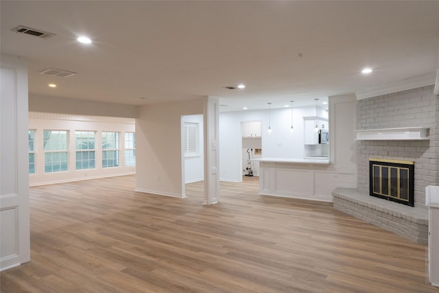18007 Ravenfield Dr, Houston, TX 77084 - unfurnished living room featuring light wood finished floors, visible vents, recessed lighting, and a brick fireplace