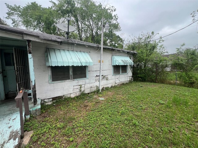 view of side of home with concrete block siding, fence, and a lawn