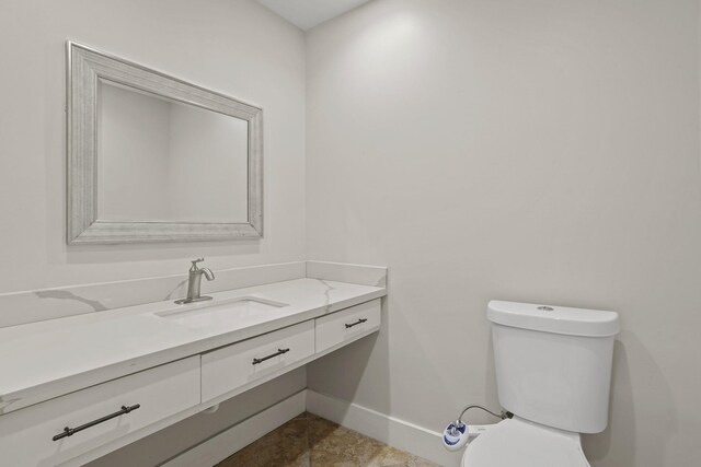 half bathroom featuring baseboards, toilet, and vanity