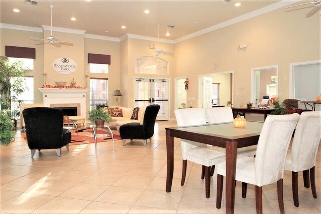2255 Braeswood Park Dr Unit 294, Houston, TX 77030 - dining room featuring a ceiling fan, a towering ceiling, light tile patterned floors, a tiled fireplace, and ornamental molding