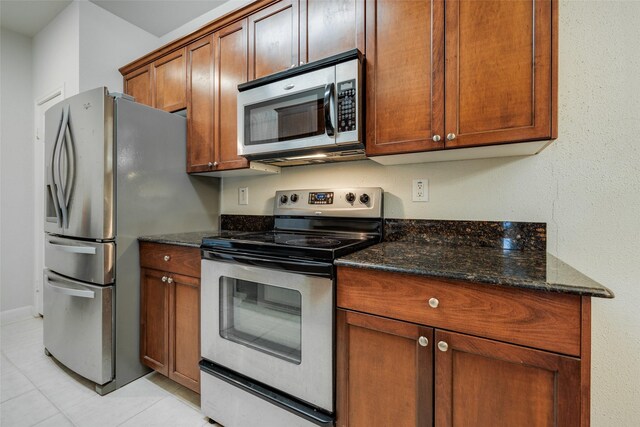 2255 Braeswood Park Dr Unit 294, Houston, TX 77030 - kitchen with appliances with stainless steel finishes, dark stone countertops, light tile patterned floors, and brown cabinetry