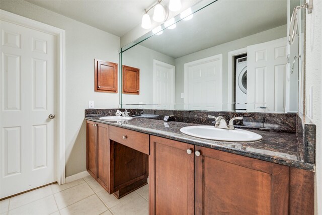 2255 Braeswood Park Dr Unit 294, Houston, TX 77030 - bathroom with estacked washer and dryer, double vanity, tile patterned floors, and baseboards