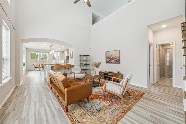 15039 Eves Necklace Ct, Cypress, TX 77433 - living area with arched walkways, light wood-style floors, a ceiling fan, and a towering ceiling