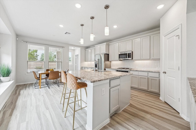 15039 Eves Necklace Ct, Cypress, TX 77433 - kitchen featuring a breakfast bar, visible vents, light wood finished floors, backsplash, and appliances with stainless steel finishes