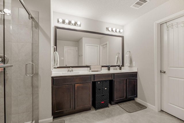 bathroom with double vanity, visible vents, a sink, baseboards, and a stall shower