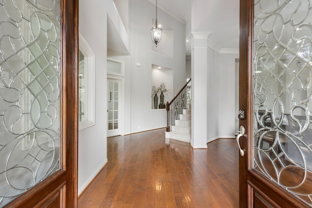 foyer entrance featuring stairway, dark wood finished floors, baseboards, ornamental molding, and ornate columns