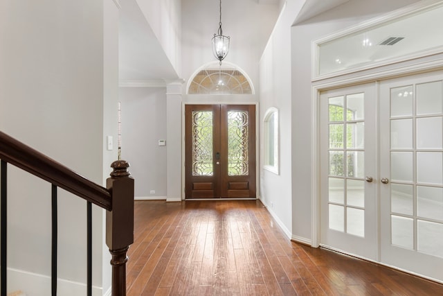 foyer entrance featuring hardwood / wood-style flooring, french doors, a high ceiling, baseboards, and visible vents
