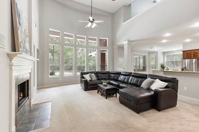 living area featuring a ceiling fan, light carpet, baseboards, and a tile fireplace