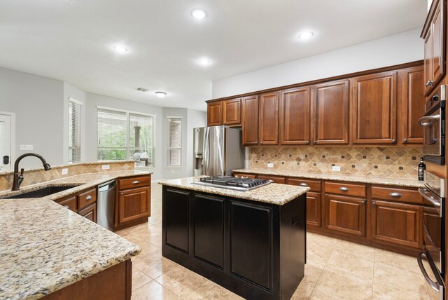 kitchen with stainless steel appliances, backsplash, a kitchen island, a sink, and light tile patterned flooring