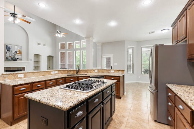 kitchen with open floor plan, a kitchen island, a sink, a ceiling fan, and appliances with stainless steel finishes