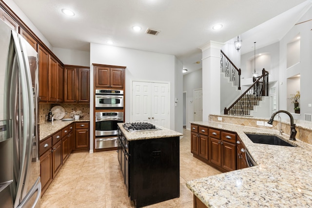 kitchen with a sink, a kitchen island, stainless steel appliances, visible vents, and decorative backsplash