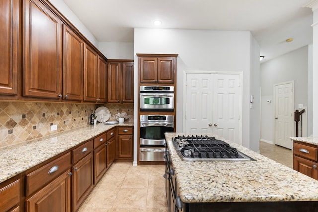 kitchen featuring backsplash, a warming drawer, stainless steel appliances, and light stone counters