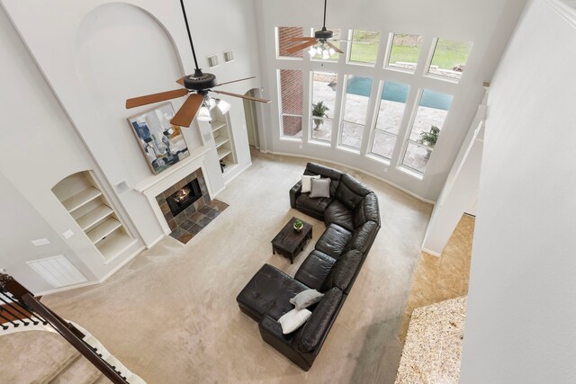 living room featuring a high ceiling, a ceiling fan, built in features, and carpet