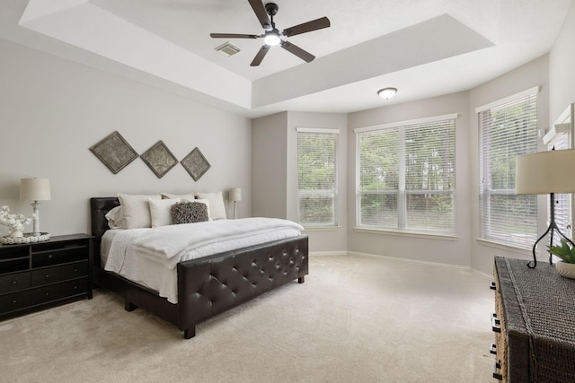carpeted bedroom with baseboards, a tray ceiling, visible vents, and ceiling fan