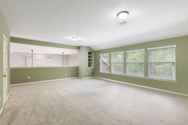 unfurnished living room with vaulted ceiling, light colored carpet, baseboards, a textured ceiling, and visible vents