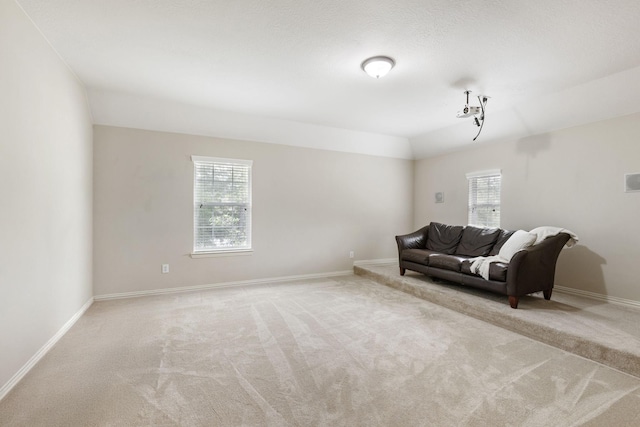carpeted living room featuring baseboards and vaulted ceiling