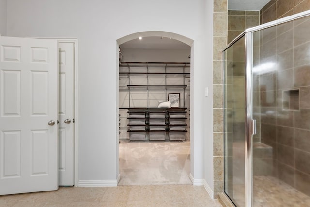 full bath with a stall shower, baseboards, and tile patterned flooring
