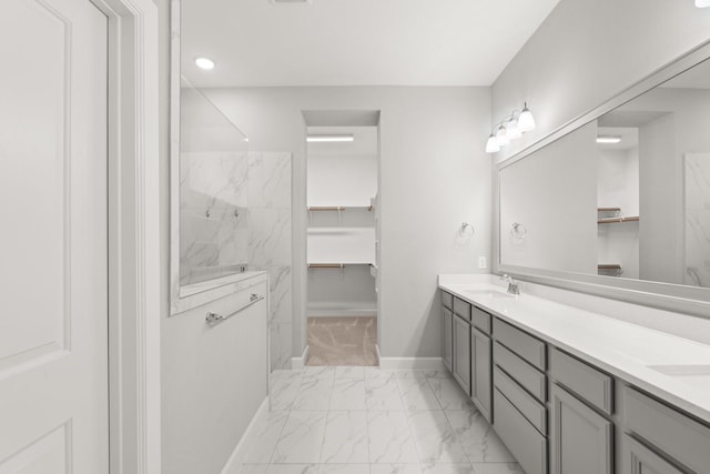 bathroom featuring a sink, a marble finish shower, a spacious closet, marble finish floor, and double vanity