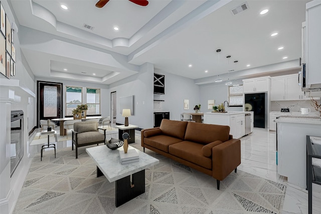 living room with marble finish floor, a tray ceiling, visible vents, and recessed lighting