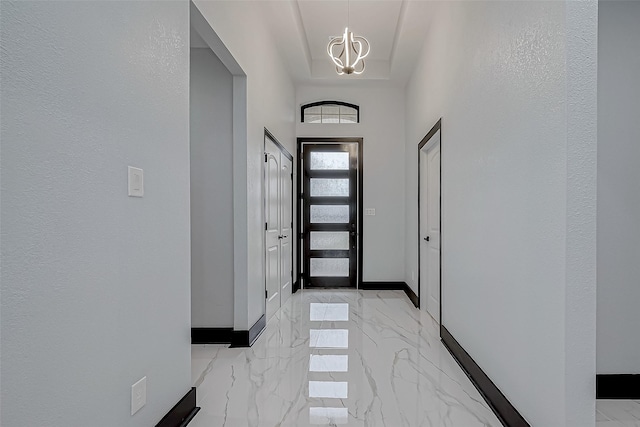 foyer with baseboards, marble finish floor, and a chandelier