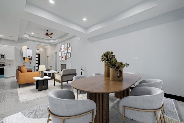 dining room with a tray ceiling, marble finish floor, ceiling fan, and recessed lighting