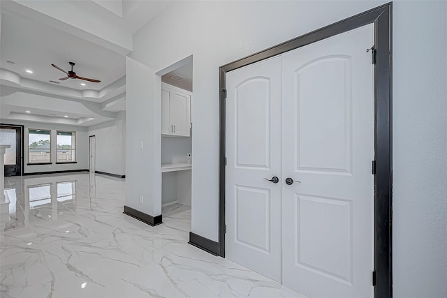 hall featuring marble finish floor, baseboards, a raised ceiling, and recessed lighting