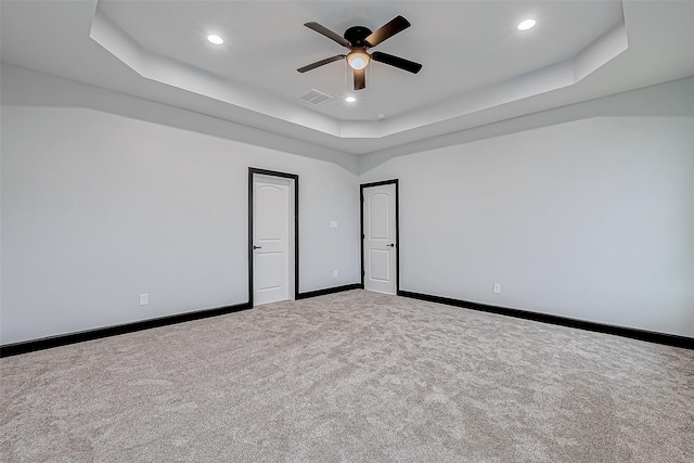 empty room with a tray ceiling, recessed lighting, baseboards, carpet floors, and ceiling fan