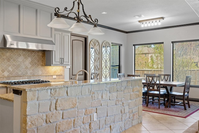 12606 Mostyn Ct, Magnolia, TX 77354 - kitchen with stainless steel gas cooktop, decorative backsplash, range hood, light tile patterned floors, and light stone countertops