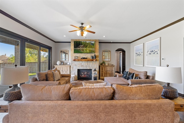 12606 Mostyn Ct, Magnolia, TX 77354 - living area featuring a stone fireplace, crown molding, a ceiling fan, and arched walkways