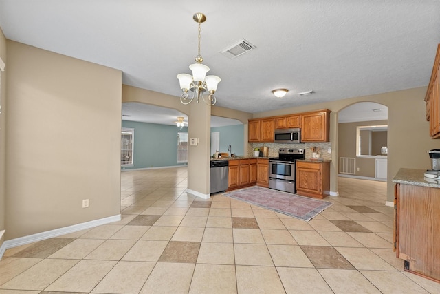 1231 Kings Creek Trl, Missouri City, TX 77459 - kitchen with arched walkways, light tile patterned floors, visible vents, and appliances with stainless steel finishes