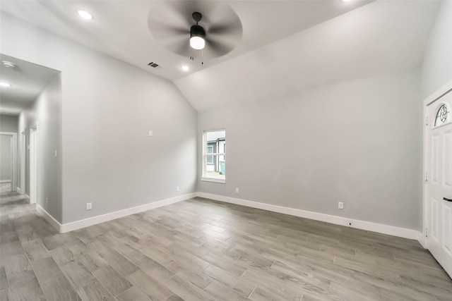 empty room featuring baseboards, vaulted ceiling, light wood-style floors, and a ceiling fan