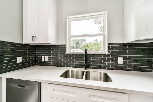kitchen featuring dishwasher, a sink, white cabinetry, and backsplash
