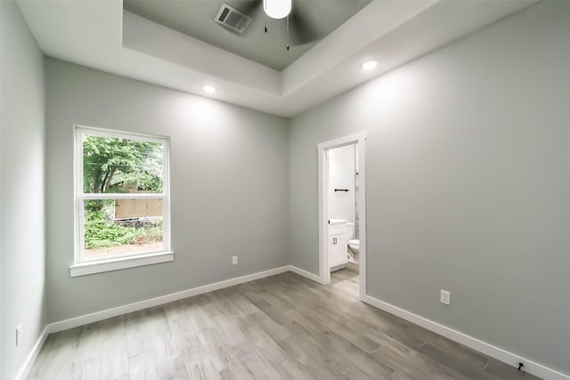 unfurnished room featuring recessed lighting, light wood-type flooring, baseboards, a raised ceiling, and a ceiling fan