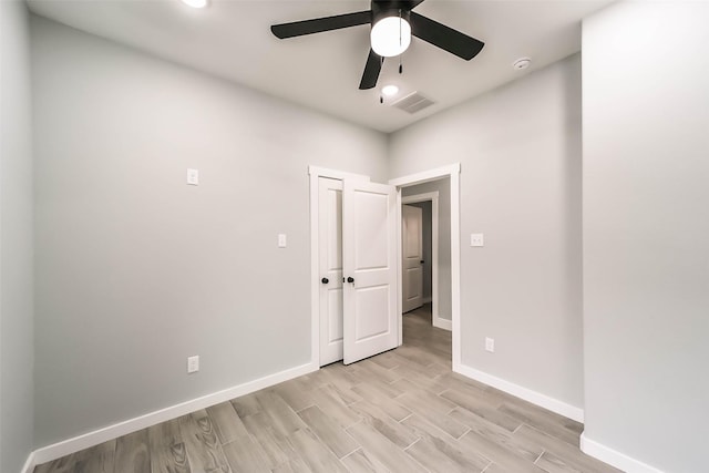 empty room featuring ceiling fan, baseboards, light wood finished floors, and visible vents