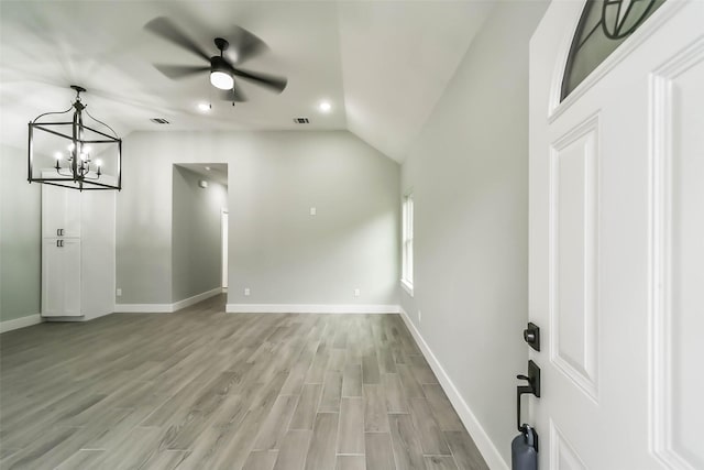 interior space featuring light wood-style flooring, baseboards, vaulted ceiling, and visible vents