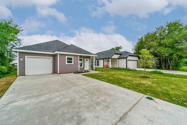 view of front of house featuring driveway, an attached garage, roof with shingles, and a front yard