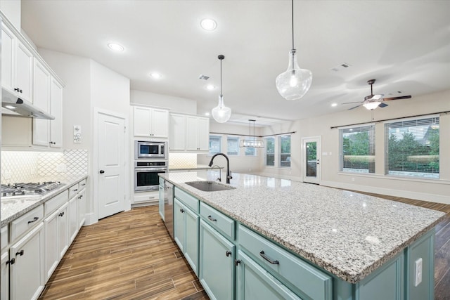 31021 Harvest Meadow Ln, Spring, TX 77386 - kitchen with stainless steel appliances, white cabinets, under cabinet range hood, wood finished floors, and recessed lighting