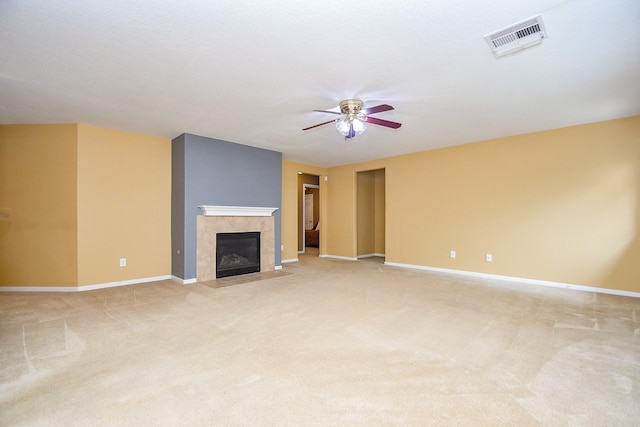 unfurnished living room featuring visible vents, light carpet, baseboards, a tiled fireplace, and a ceiling fan