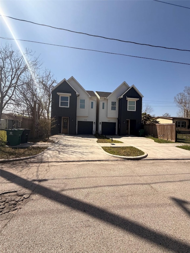 view of front of property featuring concrete driveway, fence, and an attached garage
