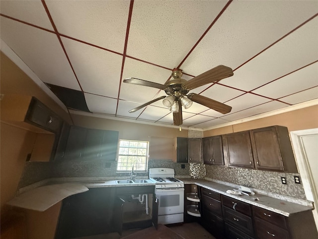 kitchen with light countertops, white gas stove, a ceiling fan, tasteful backsplash, and a sink