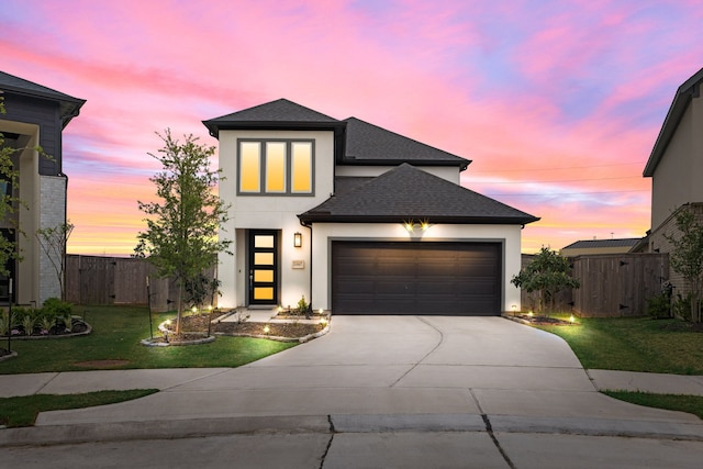 view of front of property featuring stucco siding, fence, an attached garage, driveway, and a front yard