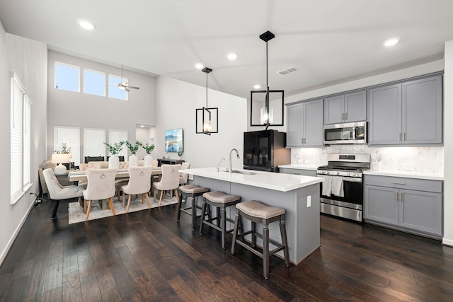 kitchen featuring open floor plan, a breakfast bar area, stainless steel appliances, gray cabinetry, and visible vents