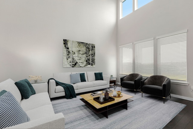 living area featuring baseboards, a towering ceiling, and wood finished floors