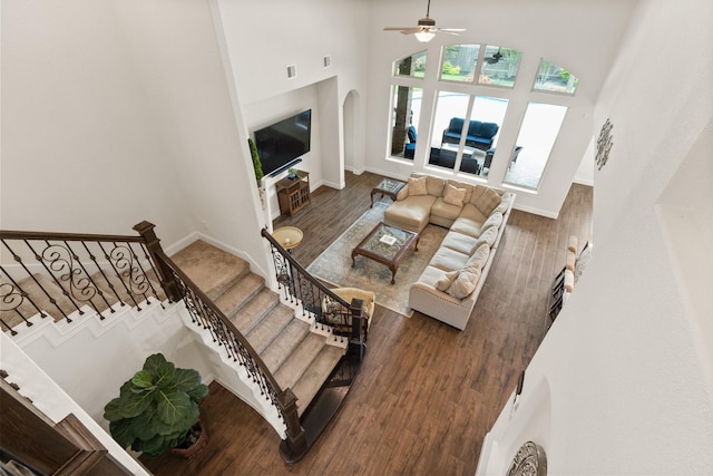 1002 Timberland Bay Ct, Pinehurst, TX 77362 - living room featuring arched walkways, a towering ceiling, a ceiling fan, stairway, and wood finished floors