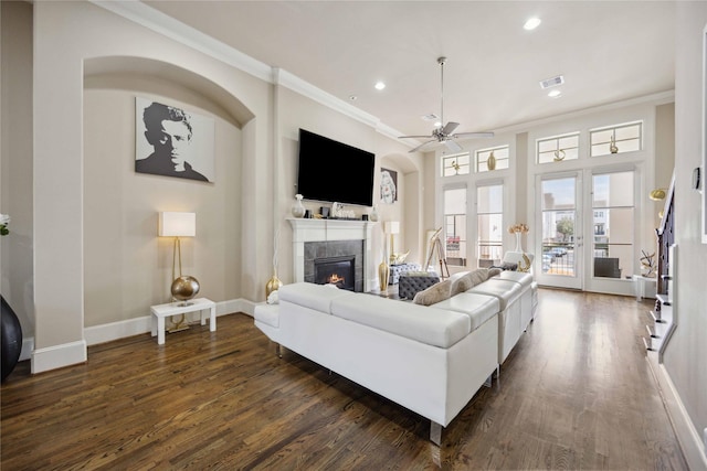 living room with a tiled fireplace, ornamental molding, dark wood-style floors, and visible vents
