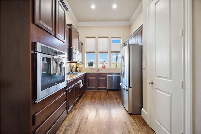 kitchen featuring a sink, light countertops, ornamental molding, and appliances with stainless steel finishes
