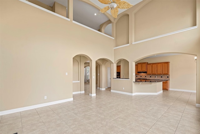 11812 Sea Shadow Bnd, Pearland, TX 77584 - unfurnished living room with light tile patterned floors, a towering ceiling, and arched walkways