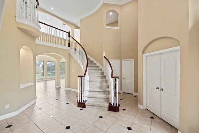 11812 Sea Shadow Bnd, Pearland, TX 77584 - foyer entrance featuring a towering ceiling, arched walkways, light tile patterned flooring, stairs, and crown molding