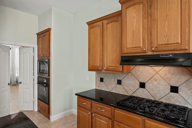 11812 Sea Shadow Bnd, Pearland, TX 77584 - kitchen with under cabinet range hood, black appliances, dark stone counters, light tile patterned floors, and tasteful backsplash